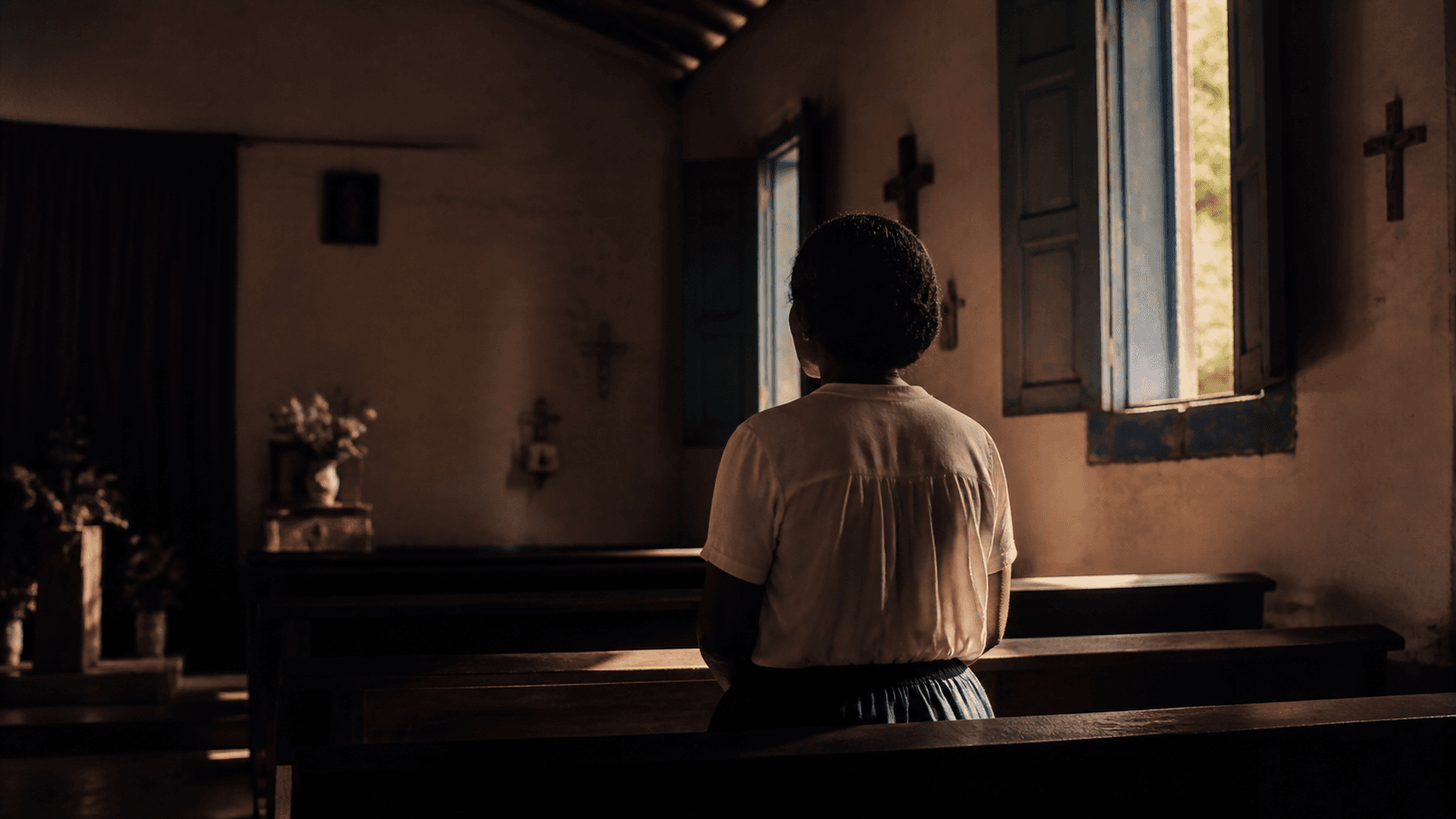 Figure seen from behind inside a chapel with warm window light