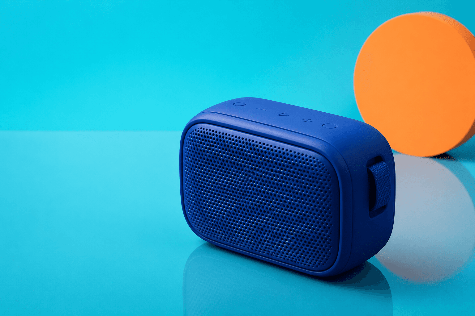 Matte blue portable speaker photographed on a cyan studio set